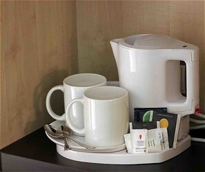 A coffee maker with two white mugs and a spoon on a tray, along with a packet of coffee pods. - Holiday Inn Express Madrid-Alcobendas by IHG (Alcobendas)