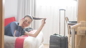 Una habitación de hotel con una cama, una maleta y un escritorio con una lámpara.