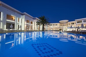 A large indoor swimming pool with a modern design, surrounded by a multi-story hotel with balconies and lounge areas. - Mythos Palace Resort & Spa - All Inclusive (Apokoronas)