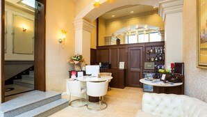 A hotel lobby with a reception desk, seating area, and a staircase leading to another floor. - Boutique Splendid Hotel (Varna)