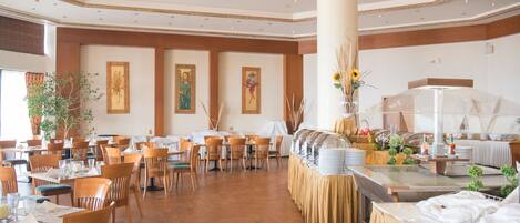 Un comedor amplio con varias mesas y sillas, una barra libre y decoración en las paredes.