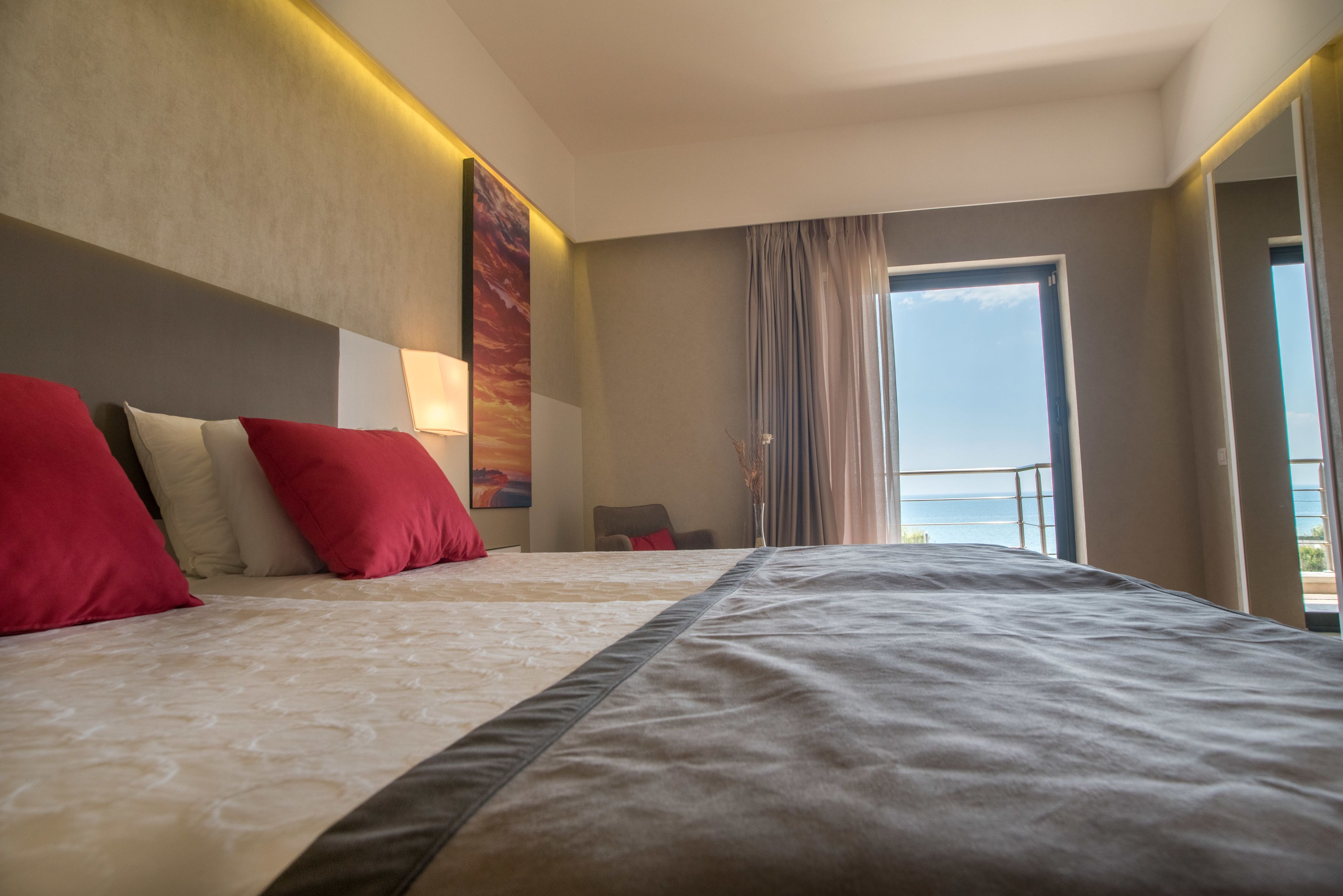 Quarto de hotel com uma cama grande, vista para o mar e varanda.