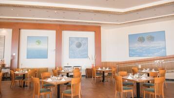 Un ristorante con tavoli e sedie in legno, opere d'arte appese alle pareti e una scala sullo sfondo.