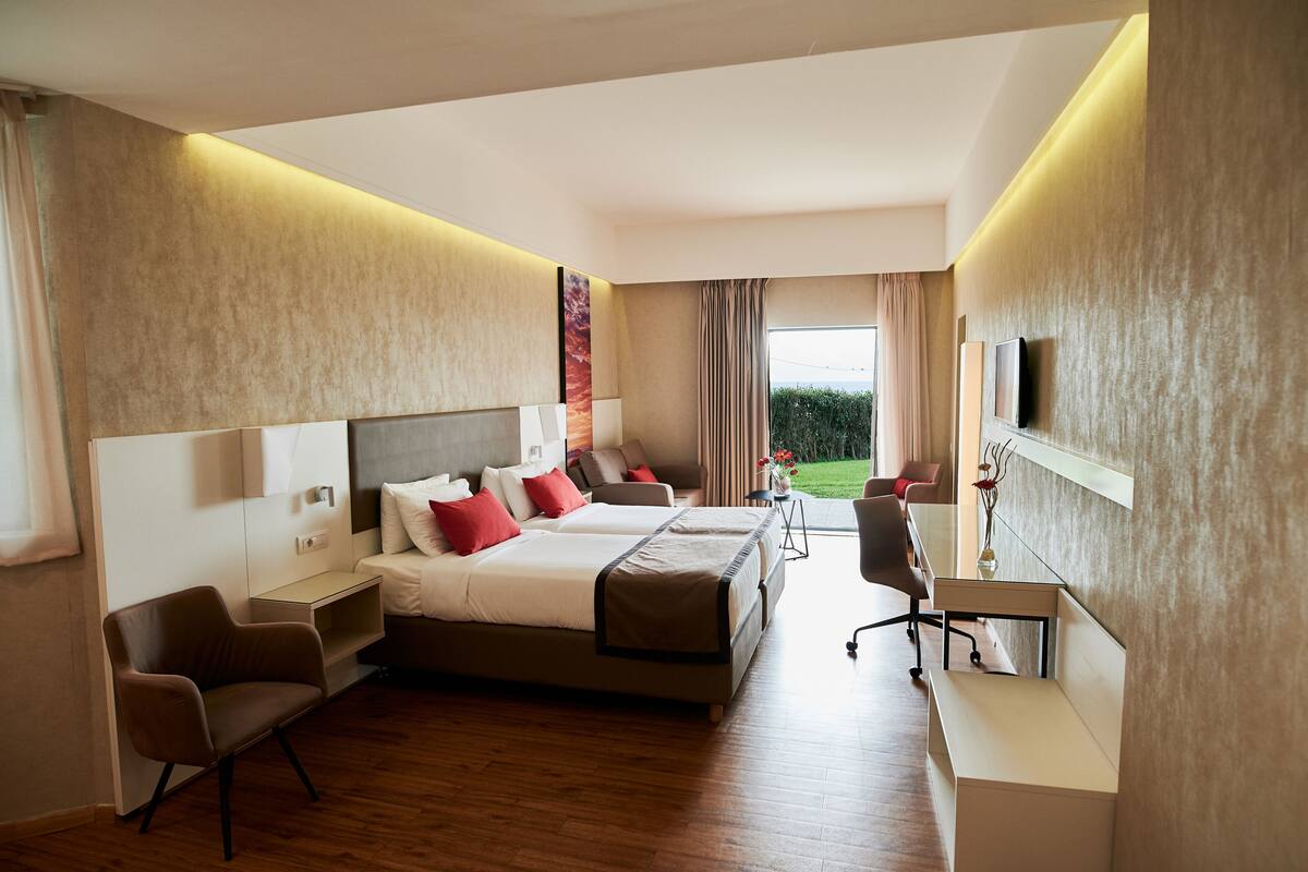 A modern hotel room with a large bed, a desk, and a chair.