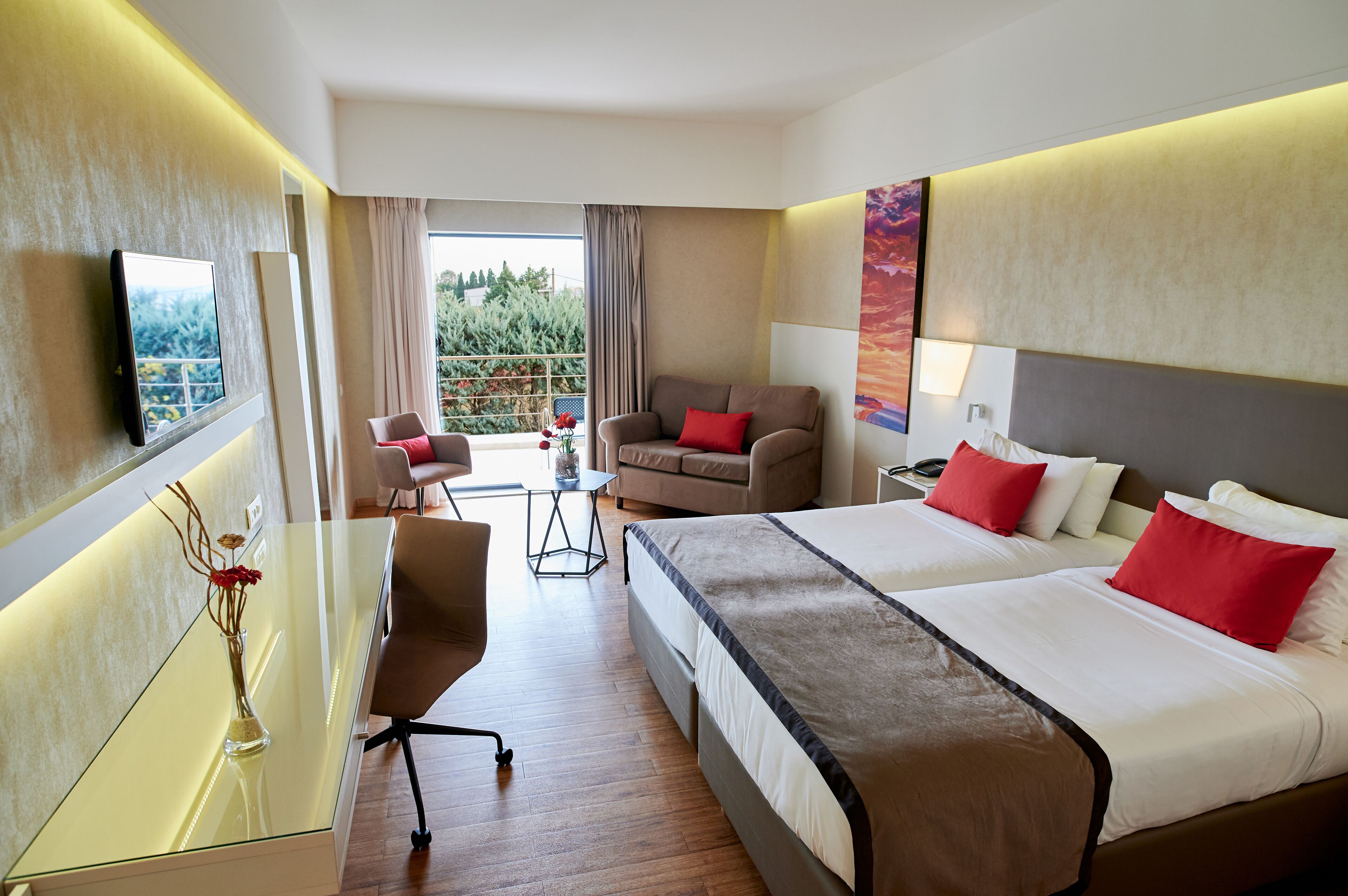 A hotel room with two beds, a sofa, a desk, and a TV.