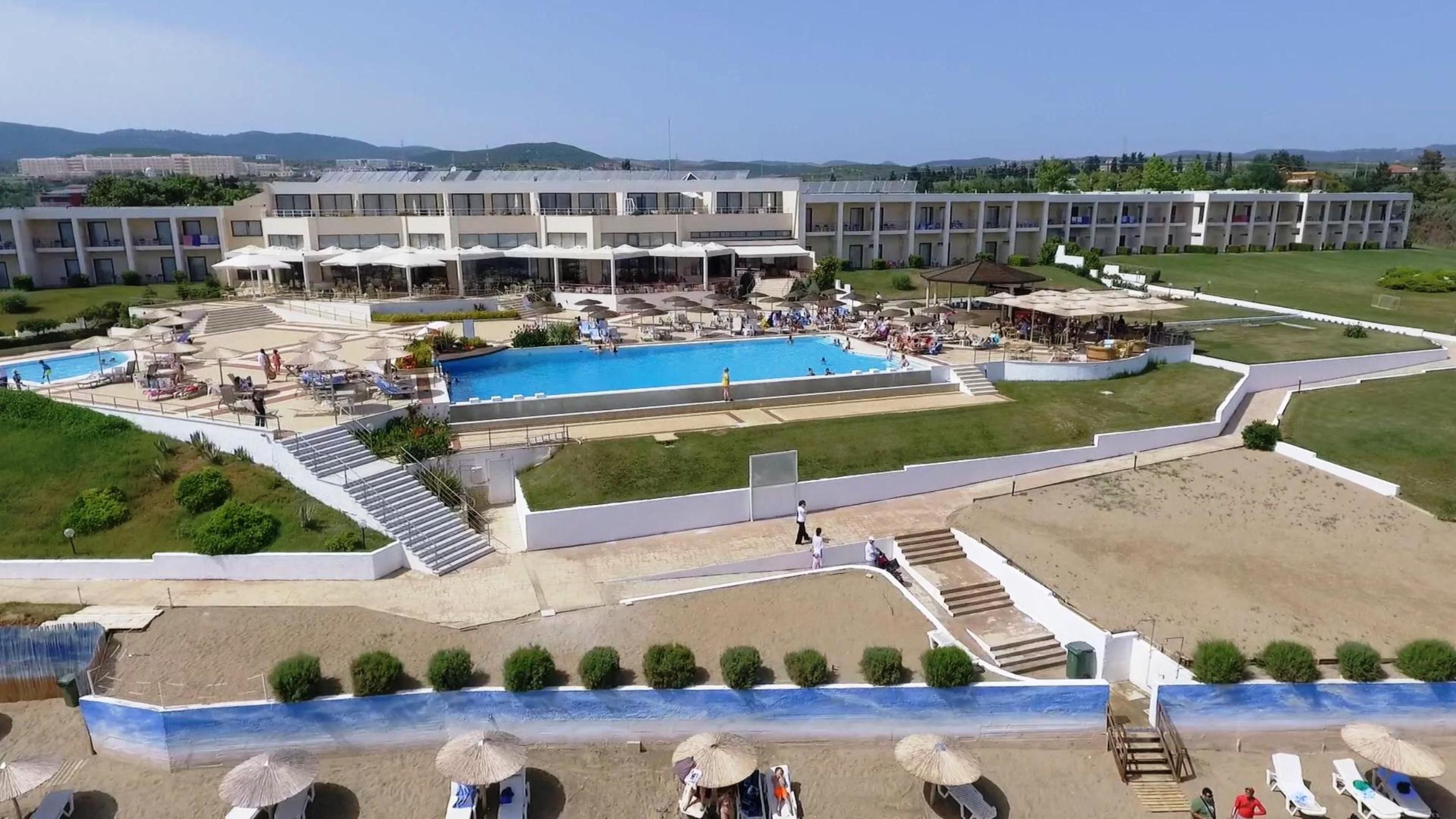 Un hôtel doté de plusieurs piscines, d’une plage et d’un grand bâtiment avec des balcons.