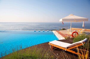 Una piscina al aire libre de temporada, sombrillas, tumbonas
