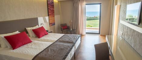 A hotel room with two beds, a chair, a TV, and a balcony with a view.