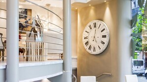 A modern interior with a spiral staircase, a large wall clock, and white furniture.