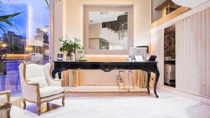 A modern room with a piano, a desk with a laptop, and a large mirror.