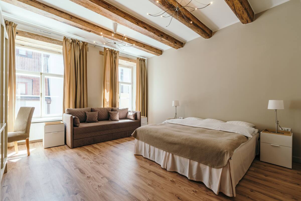 Ein Schlafzimmer mit einem Bett, einem Schlafsofa, einem Sessel, einem Nachttisch und einer Lampe.