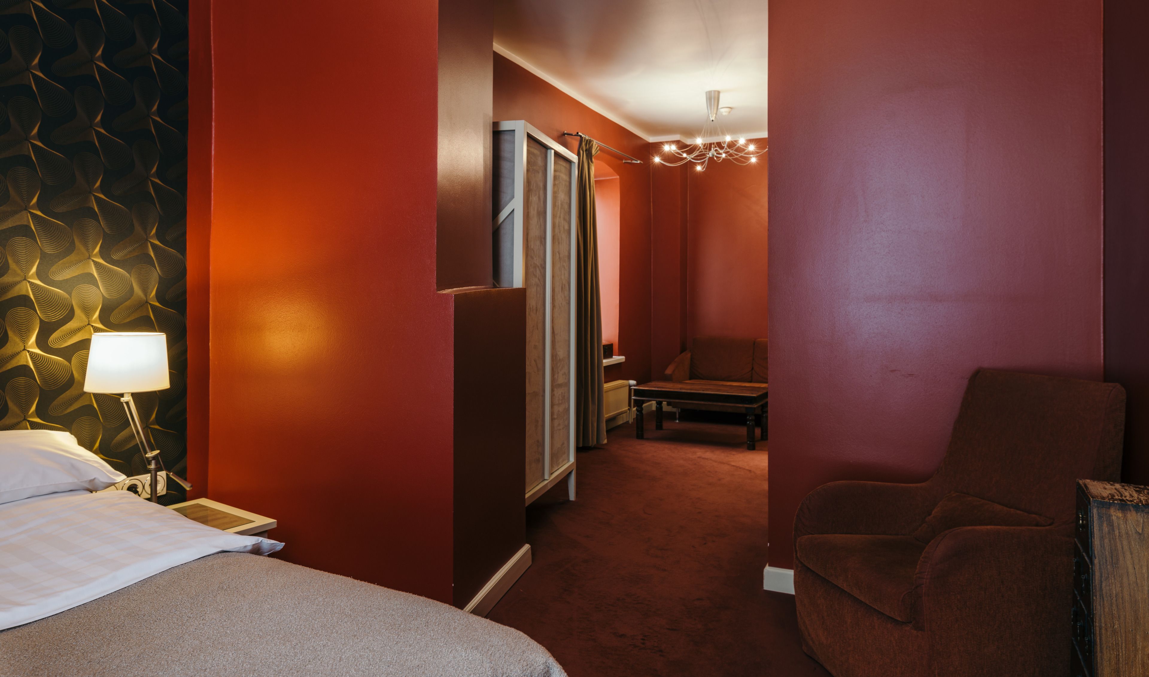 A hotel room with a bed, a chair, a desk, and a mirror.