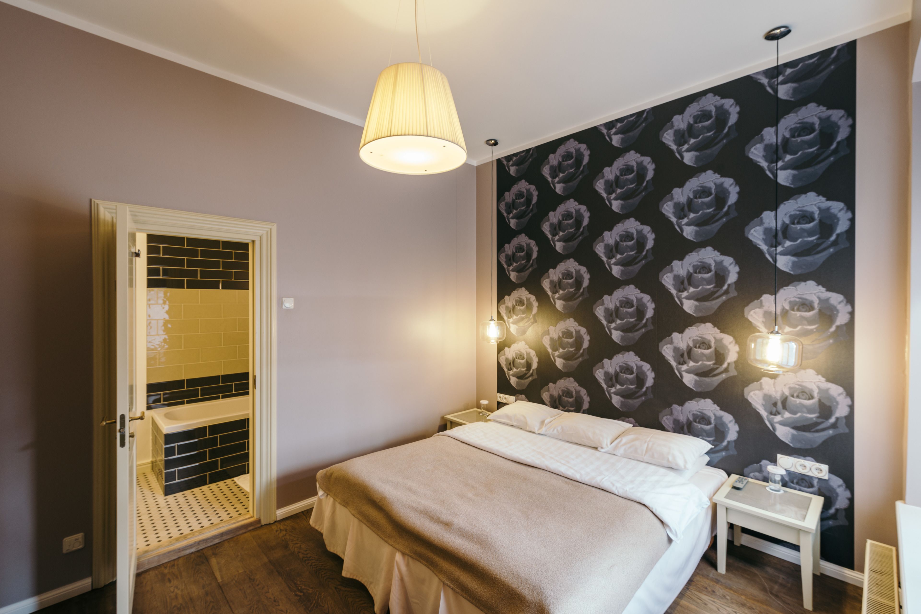 A bedroom with a bed, a nightstand, a wall-mounted light, and a door with a window.