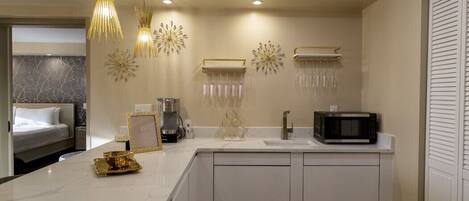 A modern kitchen with a white countertop, a microwave, hanging light fixtures, and decorative wall art.