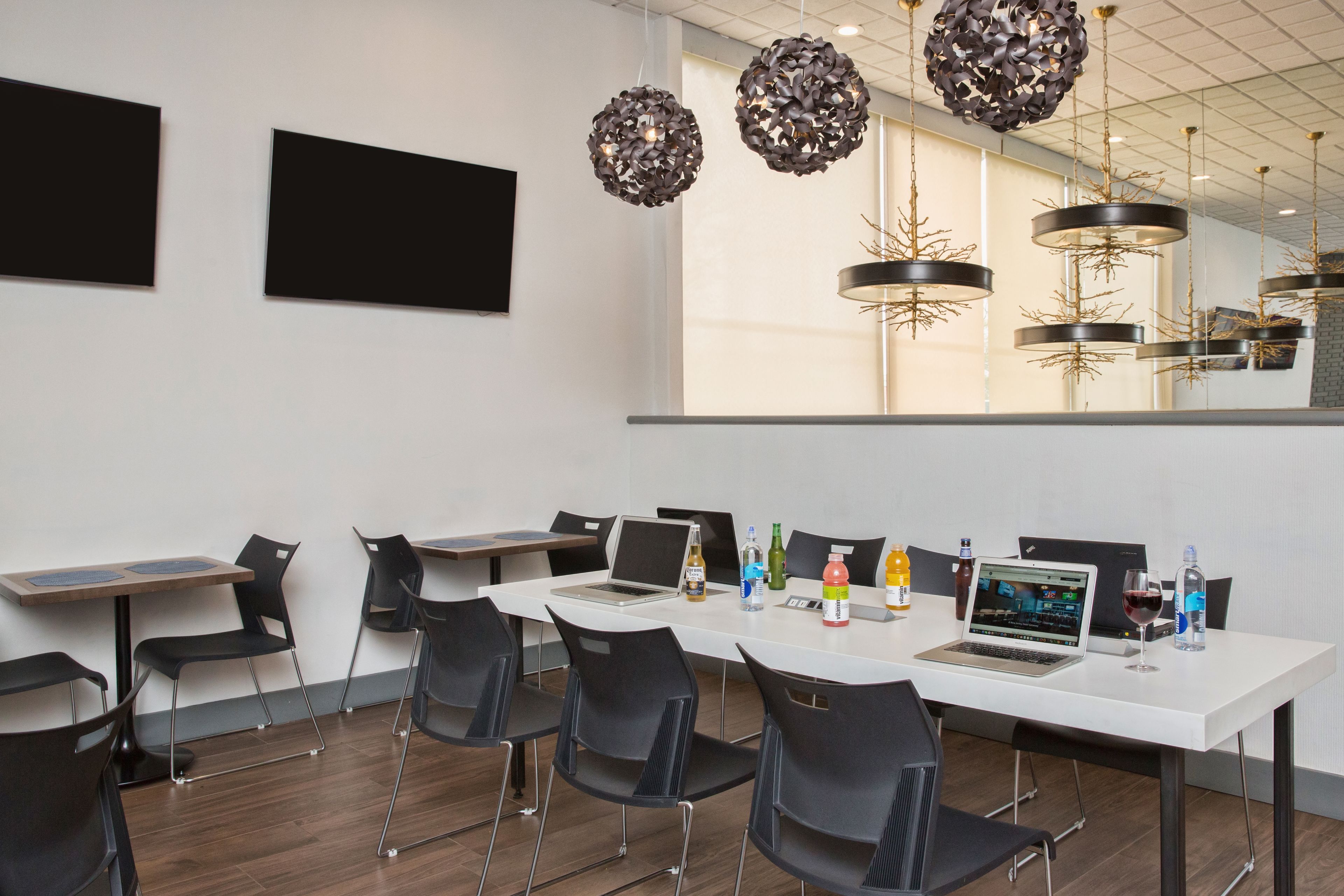 A modern conference room with white tables, black chairs, and a large window.