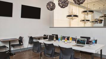 A modern conference room with white tables, black chairs, and a large window.