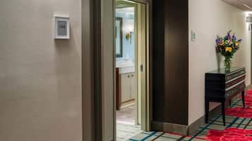 A hotel hallway with a carpeted floor, a reception desk, and a door leading to a room.