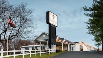 Um hotel chamado "The Kenilworth", com uma placa visível, uma cerca branca de piquete e uma bandeira americana.