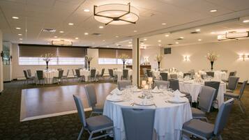 A spacious banquet hall with round tables set for dining, equipped with chairs and table settings.