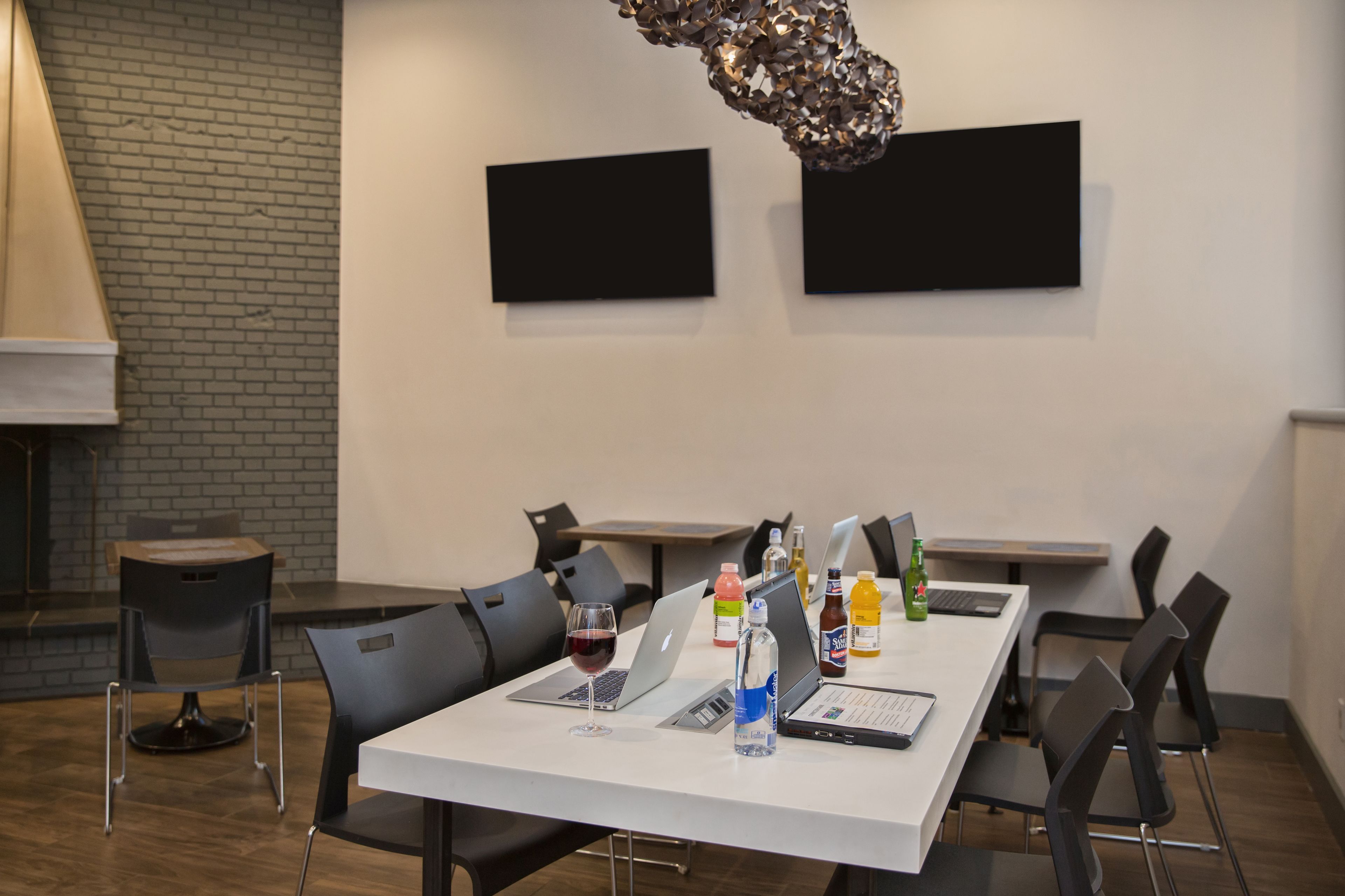 A conference room with a long table, multiple chairs, and two flat-screen TVs on the wall.