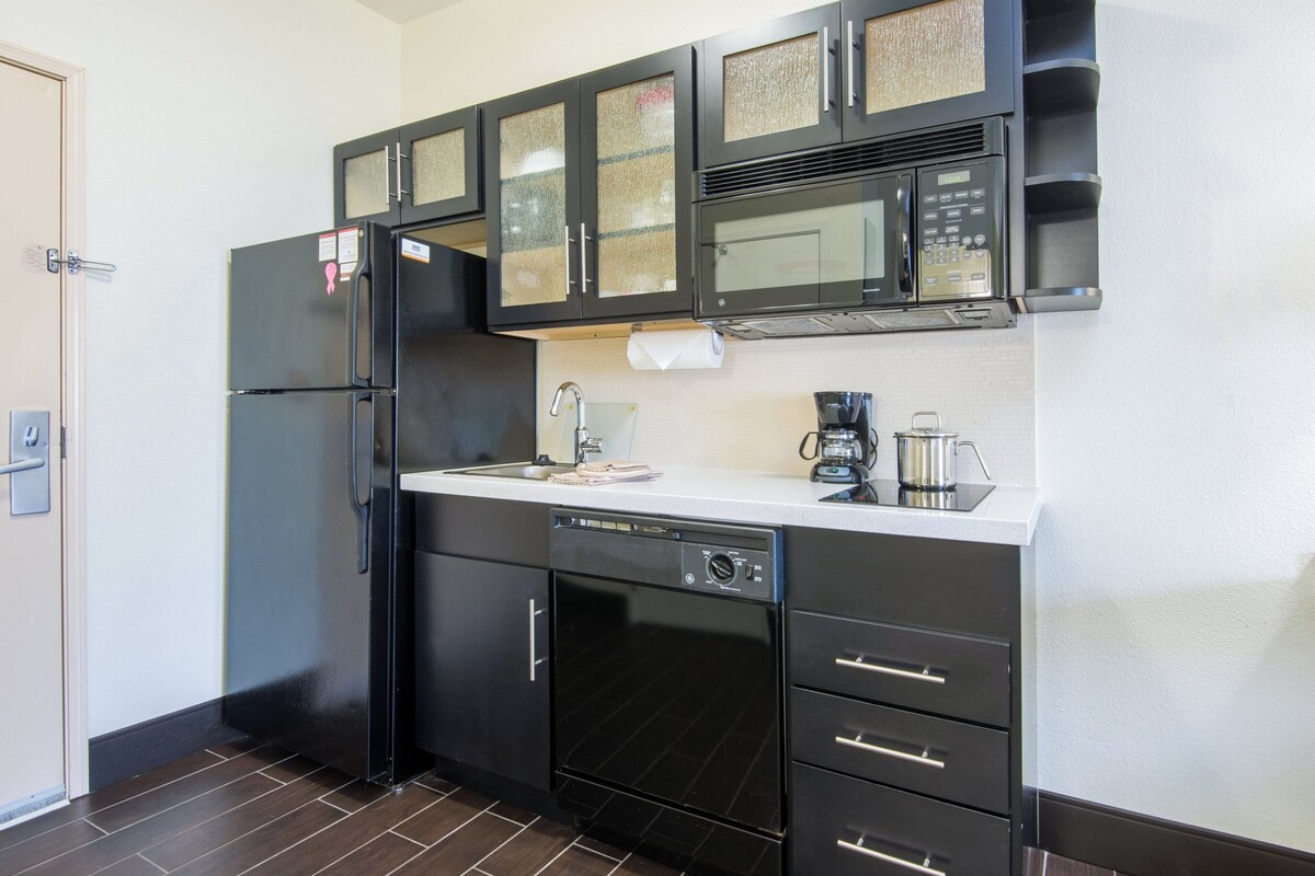 Una cocina compacta equipada con refrigerador, microondas, cafetera, lavavajillas y pileta.