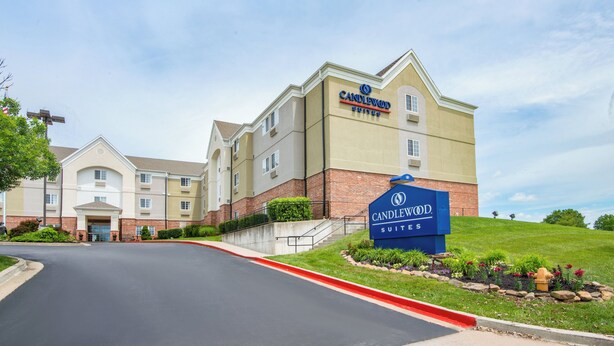 Un hôtel avec une enseigne indiquant « Candlewood Suites » et une pelouse bien entretenue à l’avant.