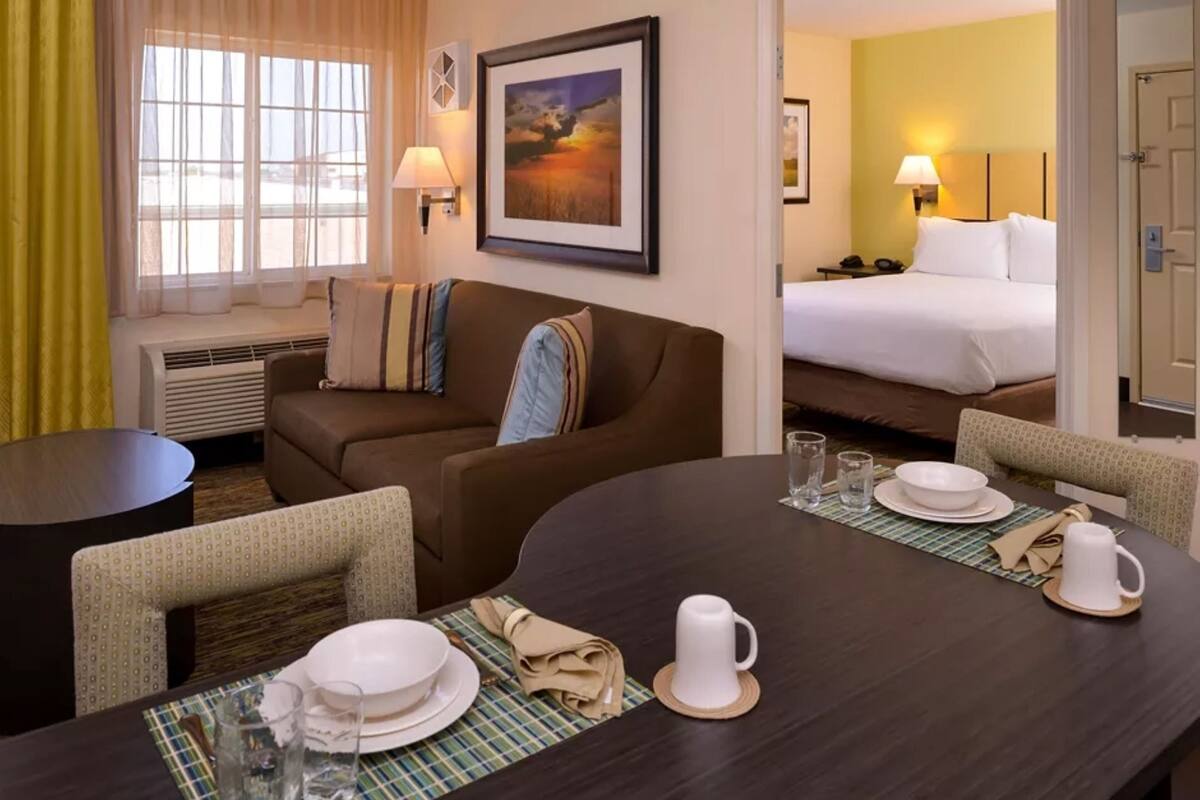 Een hotelkamer met een zithoek, een slaapbank, een bed en een schilderij aan de muur.