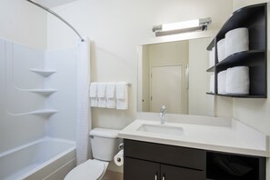 Un baño moderno con bañera, inodoro, lavabo y un perchero con varias toallas.