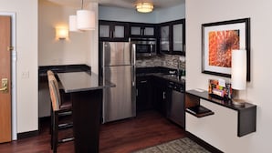 A modern kitchen with dark cabinetry, stainless steel appliances, and a marble backsplash. - Staybridge Suites Sioux Falls by IHG (Sioux Falls)