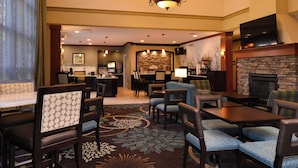 A hotel lobby with a bar area, seating arrangements, and a fireplace. - Staybridge Suites Sioux Falls by IHG (Sioux Falls)
