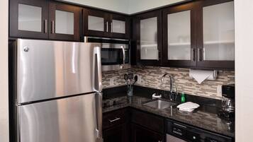 Una cocina moderna con electrodomésticos de acero inoxidable, armarios de madera oscura, salpicadero de azulejos y lavavajillas empotrado.