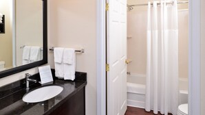 A bathroom with a sink, mirror, towel rack, and a shower area with a curtain. - Staybridge Suites Sioux Falls by IHG (Sioux Falls)