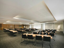 Un salón de conferencias con varias mesas y sillas, equipado con botellas de agua y tarjetas de identificación.