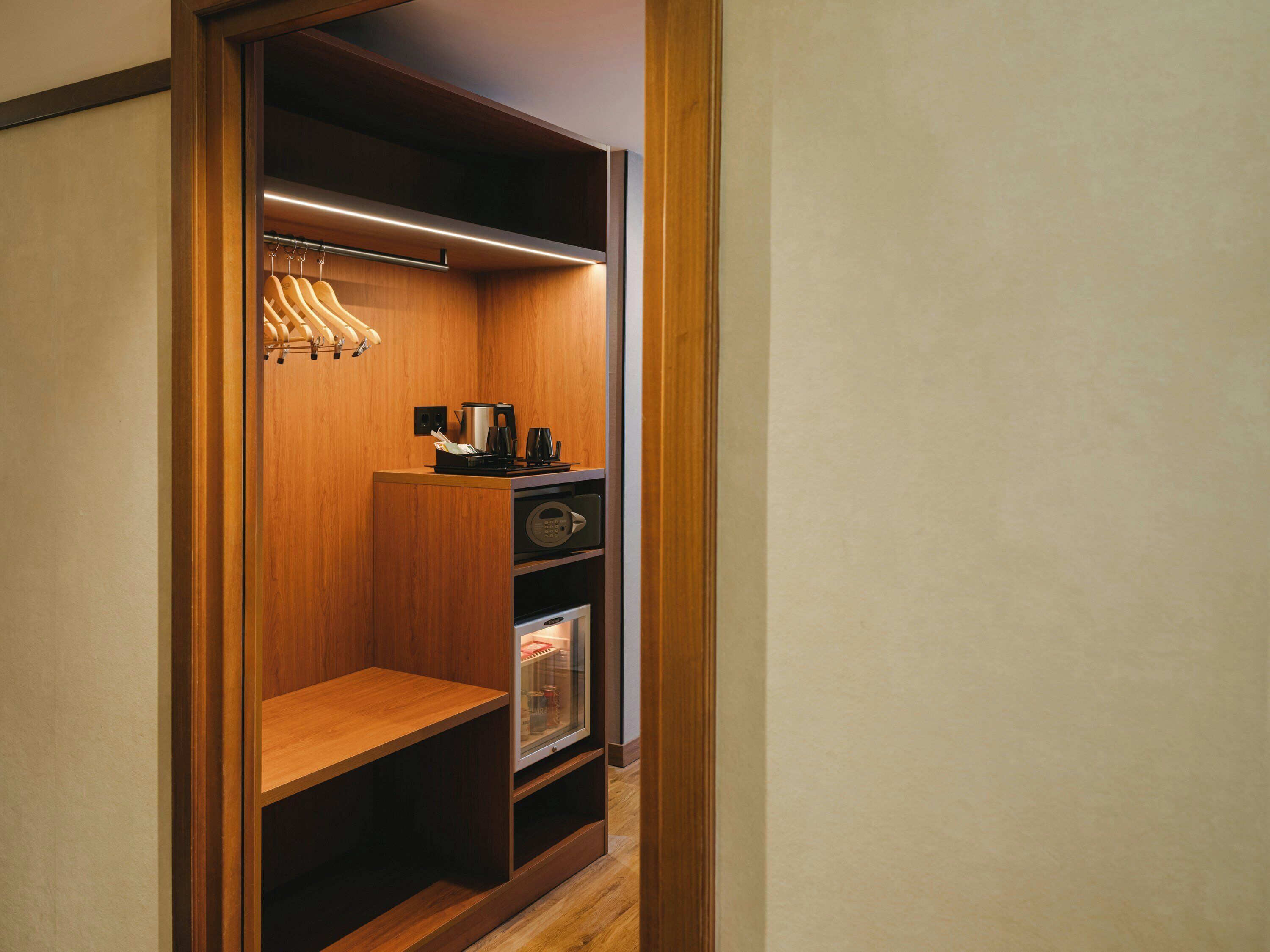 Un vestidor con estanterías de madera, una cafetera y un mueble de almacenaje con puertas de vidrio.