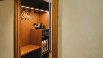 Un vestidor con estanterías de madera, una cafetera y un mueble de almacenaje con puertas de vidrio.