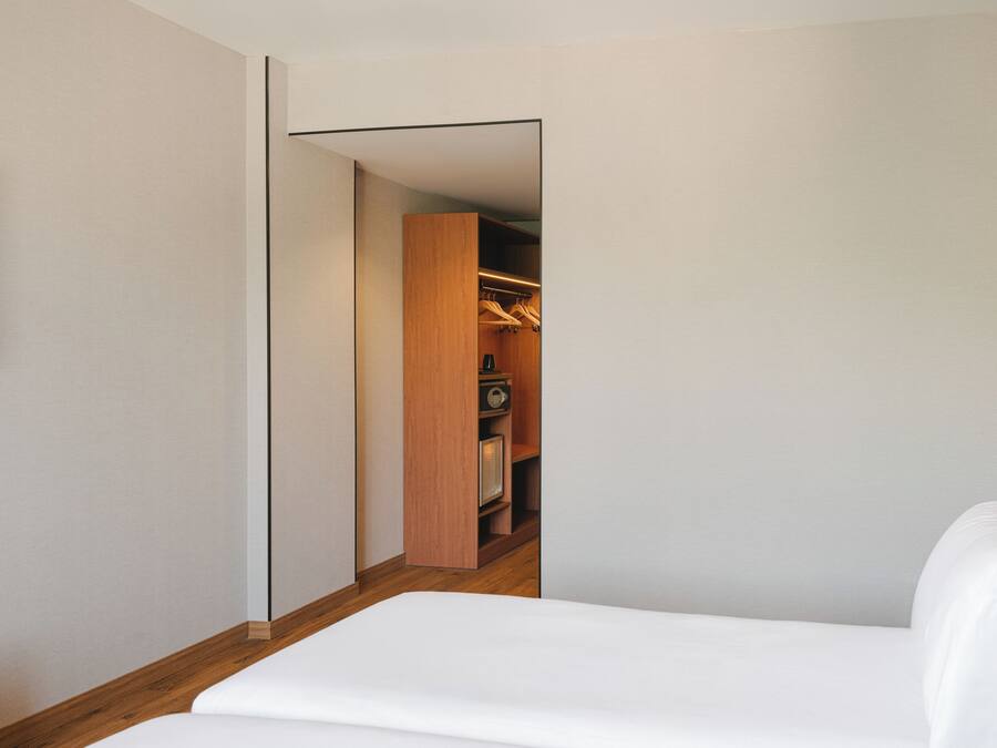 A narrow hallway leading to a closet with wooden doors and a hanging rack.