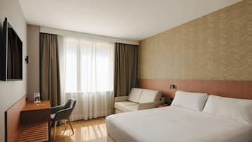 Una habitación de hotel con cama, escritorio, silla y televisión.