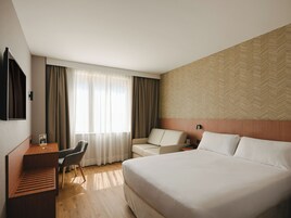Una habitación de hotel con cama, escritorio, silla y televisión.