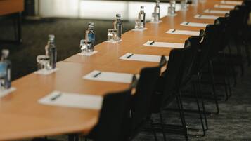 Una sala de conferencias con una mesa larga, sillas, botellas de agua y tarjetas de identificación.