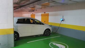 A white car parked in a parking garage with a charging station.