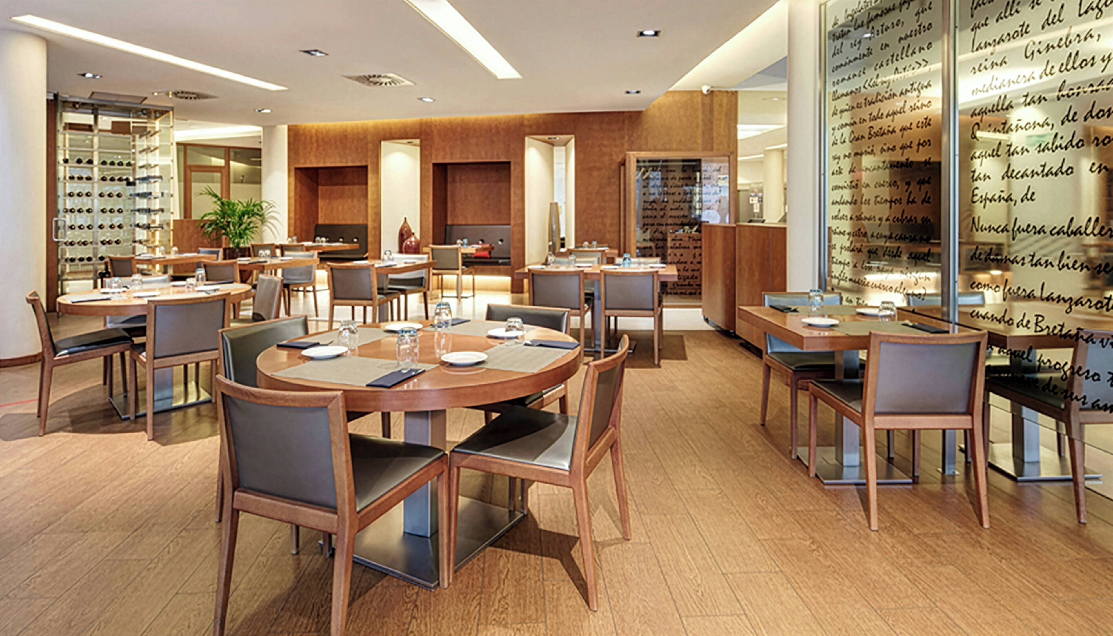A modern dining area with round tables and chairs, a wine rack, and a wall with handwritten notes.