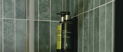 A shower gel bottle mounted on a tiled wall.