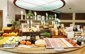 Een buffet met diverse gerechten, waaronder fruit, brood en vlees.