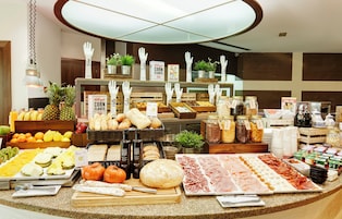 A buffet with various food items, including fruits, breads, and meats.