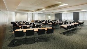 A conference room with multiple tables and chairs, equipped with water bottles and papers.