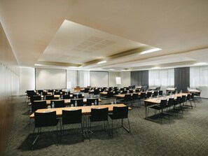 A conference room with multiple tables and chairs, equipped with water bottles and papers.