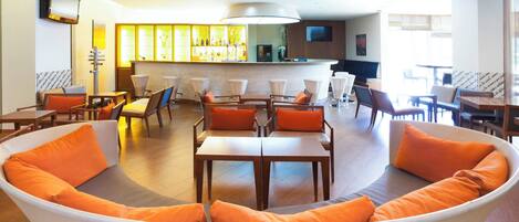 A modern hotel lobby with a curved sofa, dining tables, and a bar area.