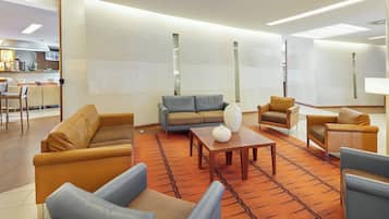 Un moderno vestíbulo de hotel con sofás de cuero, una mesa de centro de madera y una alfombra estampada.