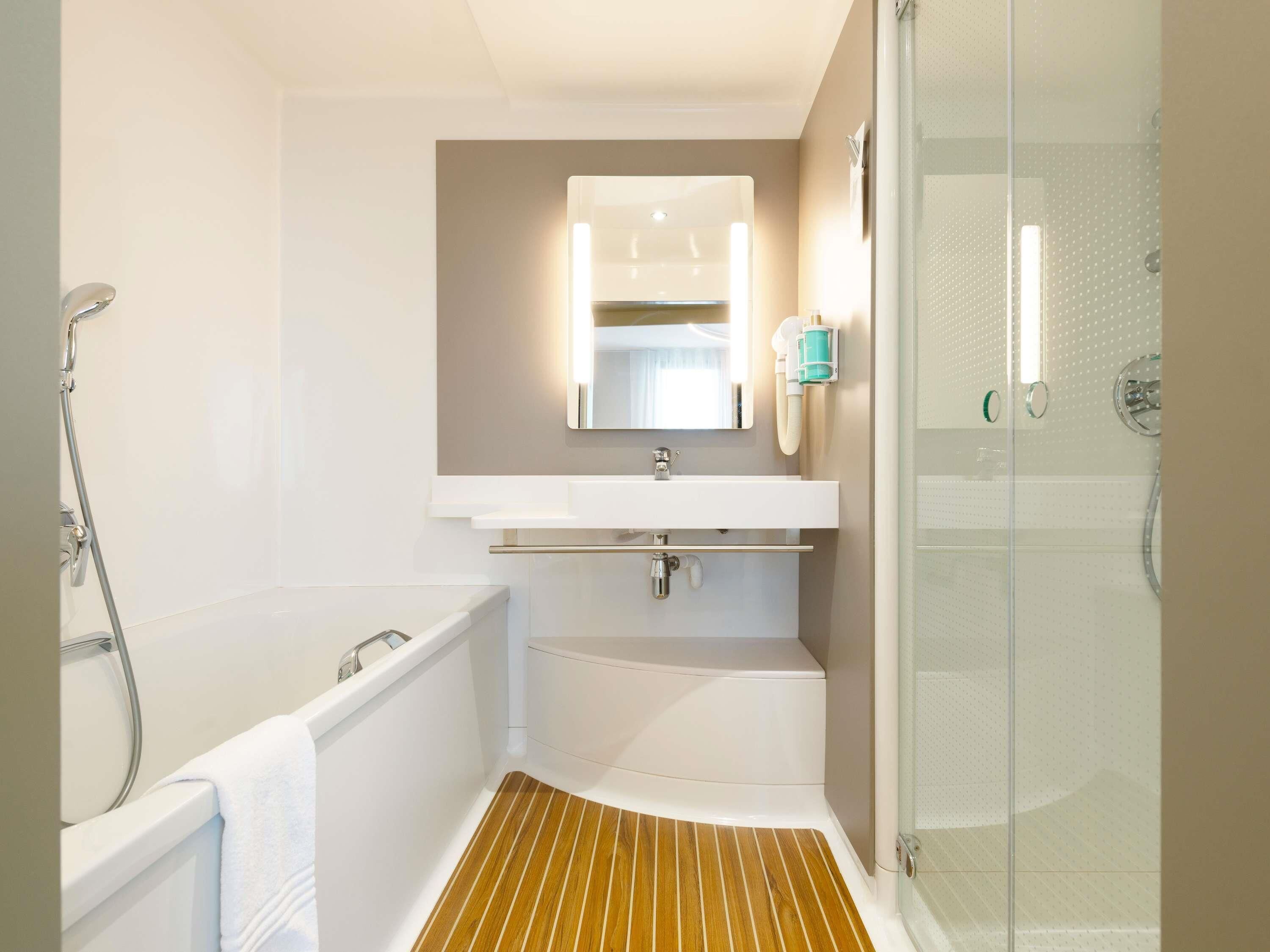 A modern bathroom with a shower, a sink, and a mirror.