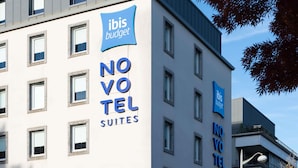 Un edificio moderno con letrero 'ibis budget', múltiples ventanas y balcones.